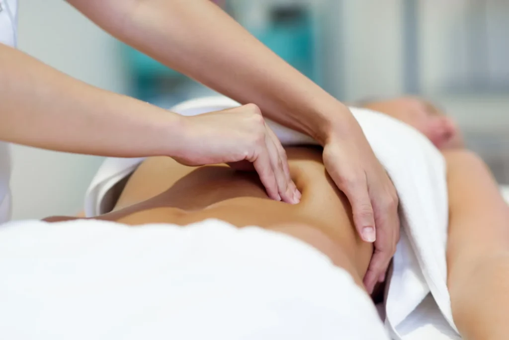 Massagem terapêutica com mãos realizando manobra de pressão nas costas de uma pessoa em um ambiente de spa, com toalha branca e foco no cuidado corporal.
